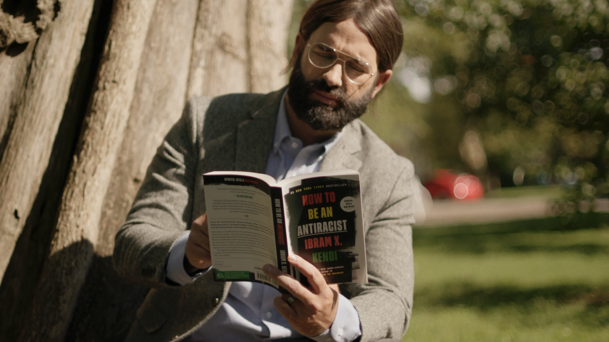 Matt Walsh dressed as a progressive person reading How to be an Antiracist by Ibram X Kendy. Courtesy: Dailywire+